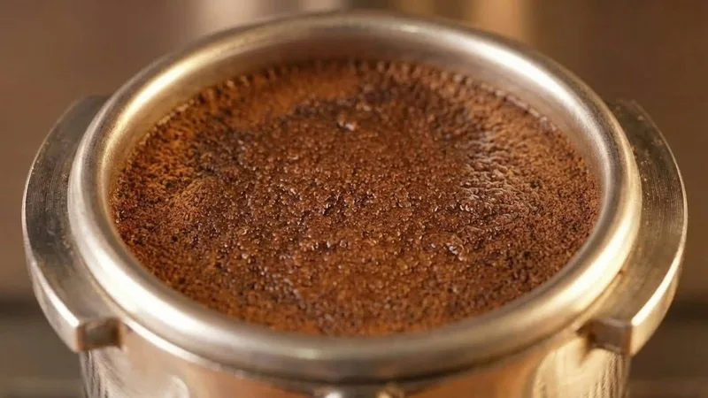 Close-up of a coffee puck mid-saturation during the pre-infusion phase, showing a wet and expanding surface
