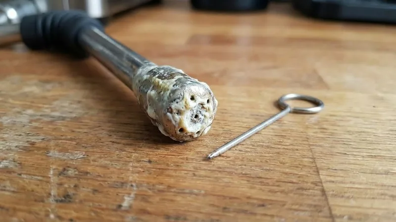 Macro shot of severe milk buildup and crust on an espresso machine steam wand tip, highlighting the need for regular cleaning