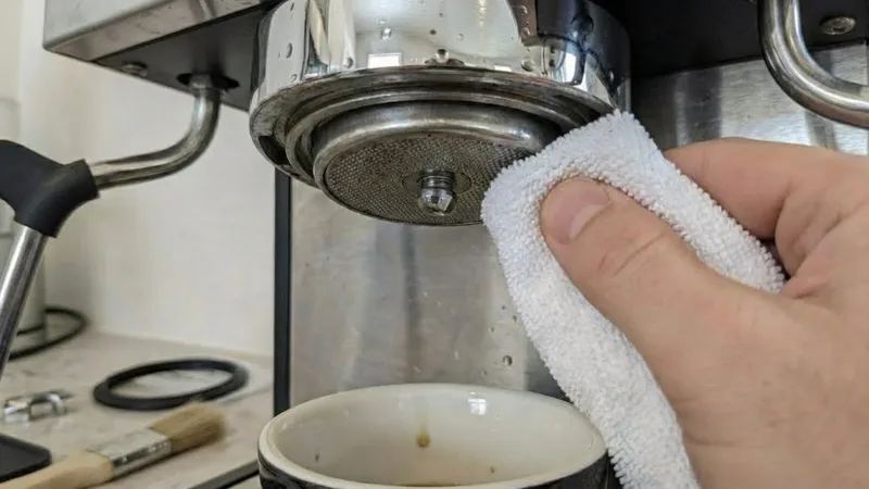 Wiping the group head gasket groove with a clean microfiber cloth to remove coffee residue and debris before installing the new seal